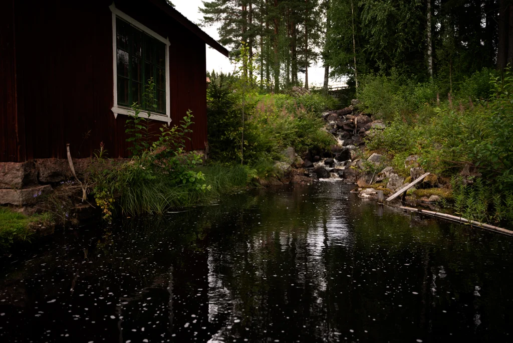 Natur med bäck och röd stuga i Hälsingland där NÅRDRÅ Sweden tillverkar och finner sin inspiration.